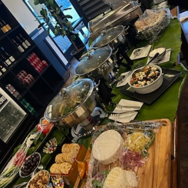 Bistro Saffron's Asian-fusion buffet spread with chafing dishes, salads, cheeses, and crackers on banana leaves.