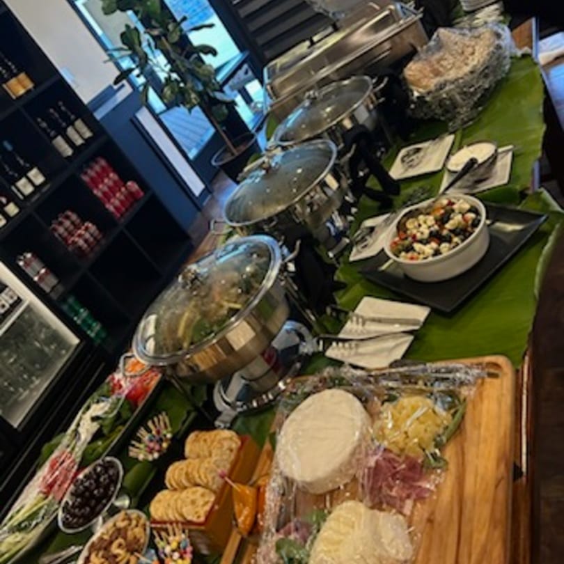 Bistro Saffron's Asian-fusion buffet spread with chafing dishes, salads, cheeses, and crackers on banana leaves.