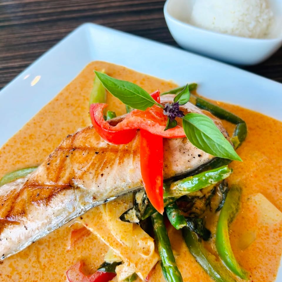Grilled salmon in red curry with green beans, red peppers, and basil, served with rice.